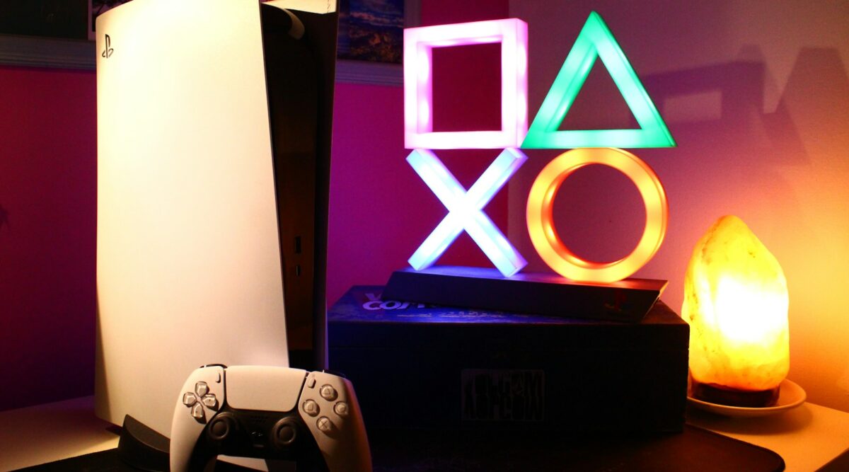 playstating con un mando y una lámpara led de colores